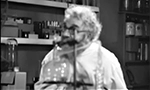 Captura de tela do filme Maniac (1934), em domínio público. A câmera está fora de foco e mostra Horace B. Carpenter como o personagem "Dr. Meirschultz" atrás de um equipamento de laboratório.